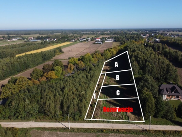 Aerial view of a trapezoidal land parcel outlined in white, divided into sections A, B, C with a reserved area labeled 'Rezerwacja' in red.