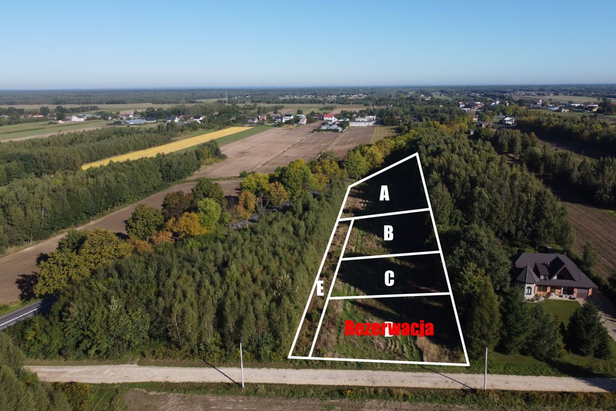 Aerial view of a trapezoidal land parcel outlined in white, divided into sections A, B, C with a reserved area labeled 'Rezerwacja' in red.