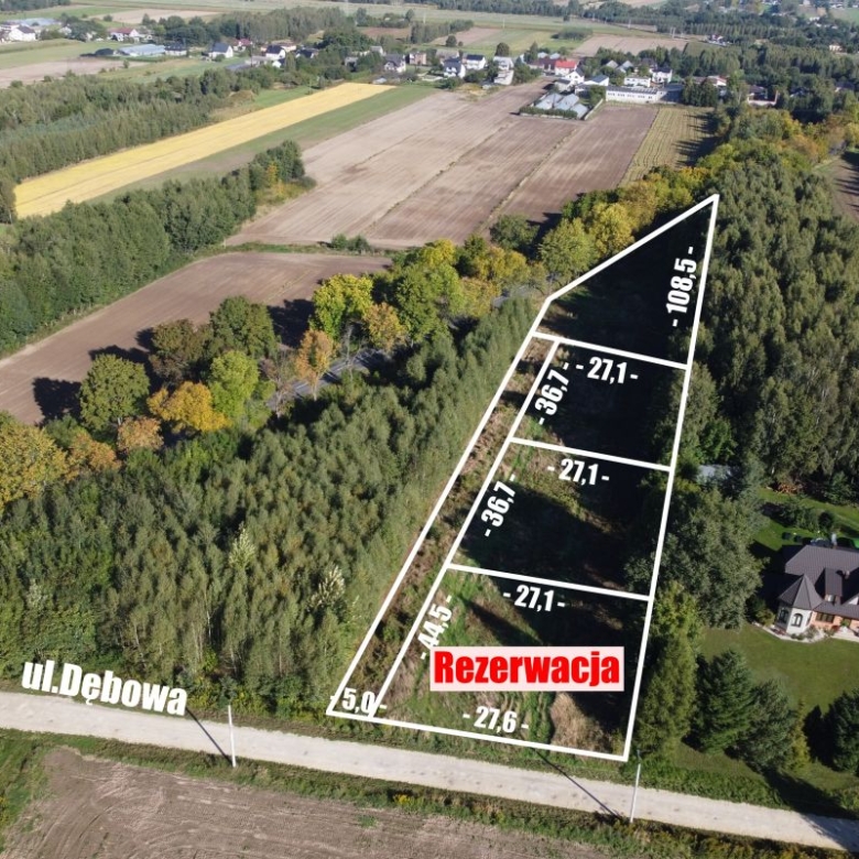 Aerial view of a triangular land parcel outlined with white borders, along Ul. Dębowa, with measurement labels and a red 'Rezerwacja' banner indicating reserved status.