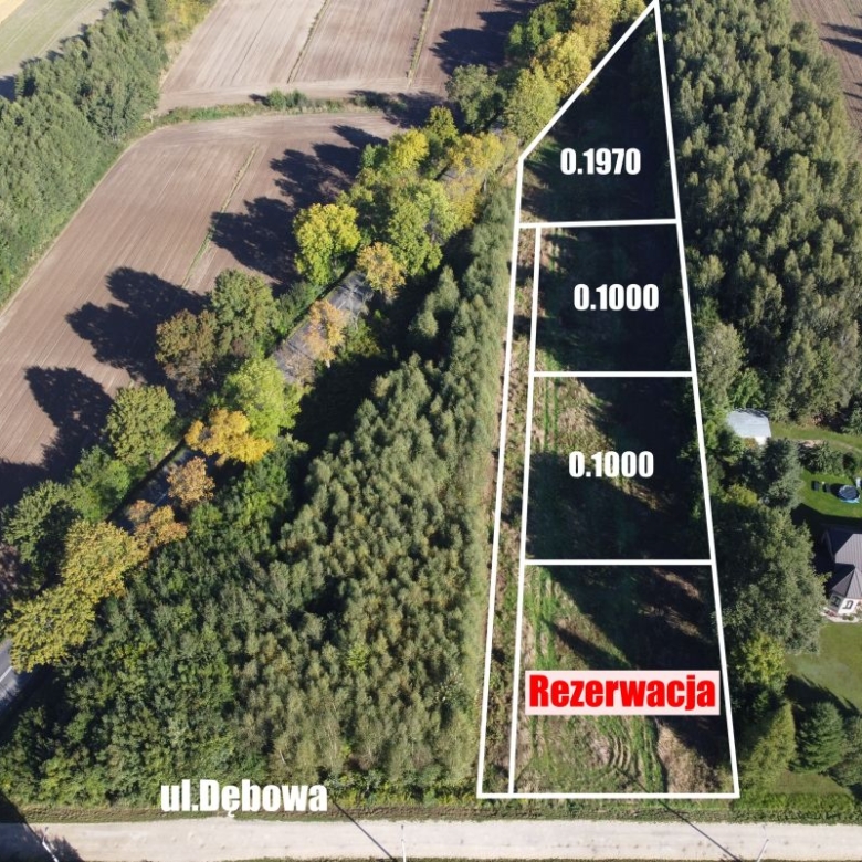 Aerial view of a triangular land parcel on ul. Dębowa, outlined in white, with sections labeled 0.1970 and 0.1000 and a red 'Rezerwacja' area.