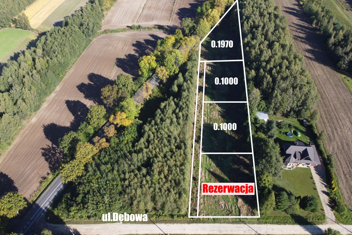 Aerial view of a triangular land parcel on ul. Dębowa, outlined in white, with sections labeled 0.1970 and 0.1000 and a red 'Rezerwacja' area.