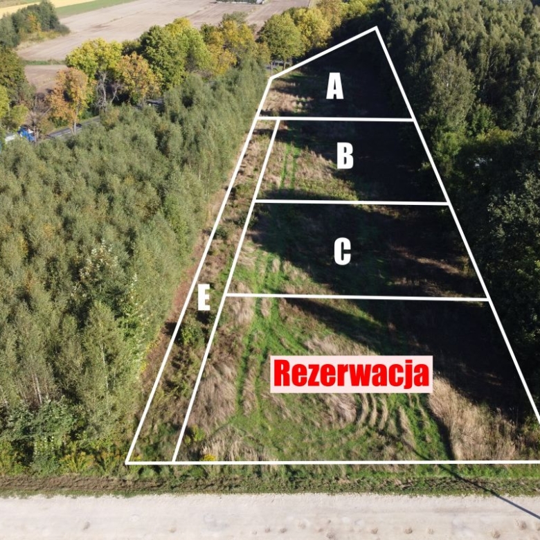 Aerial view of a triangular land plot divided into sections A, B, C, E, with the word 'Rezervacja' in red.
