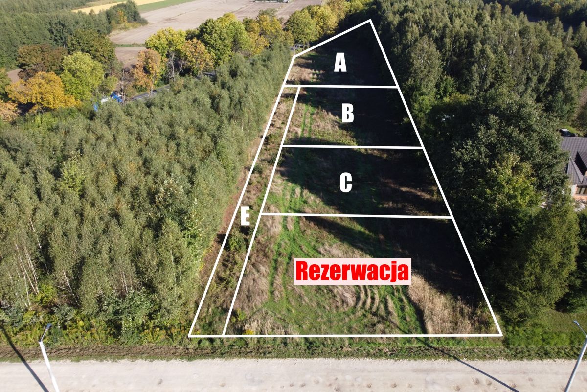 Aerial view of a triangular land plot divided into sections A, B, C, E, with the word 'Rezervacja' in red.