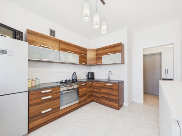 Modern L-shaped kitchen with wooden cabinets, stainless steel appliances, and a gray countertop