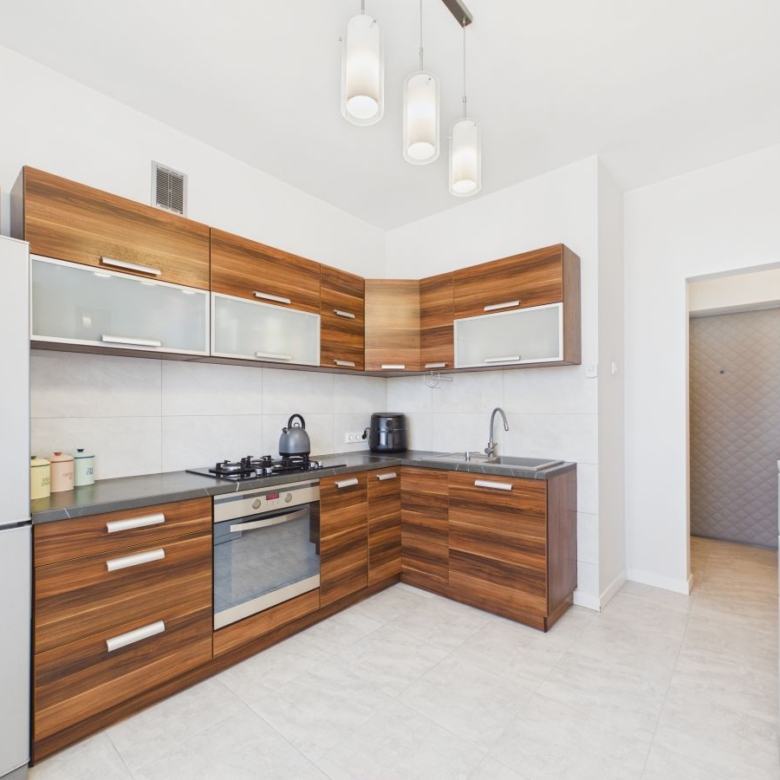 Modern L-shaped kitchen with wooden cabinets, stainless steel appliances, and a gray countertop