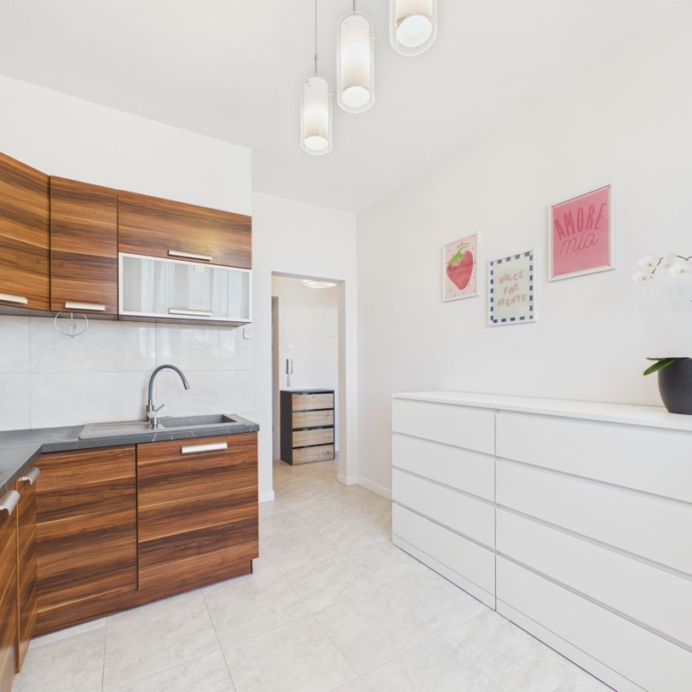 Bright modern kitchen with dark wood cabinets, gray countertop, and a white dresser on the right wall under framed art.