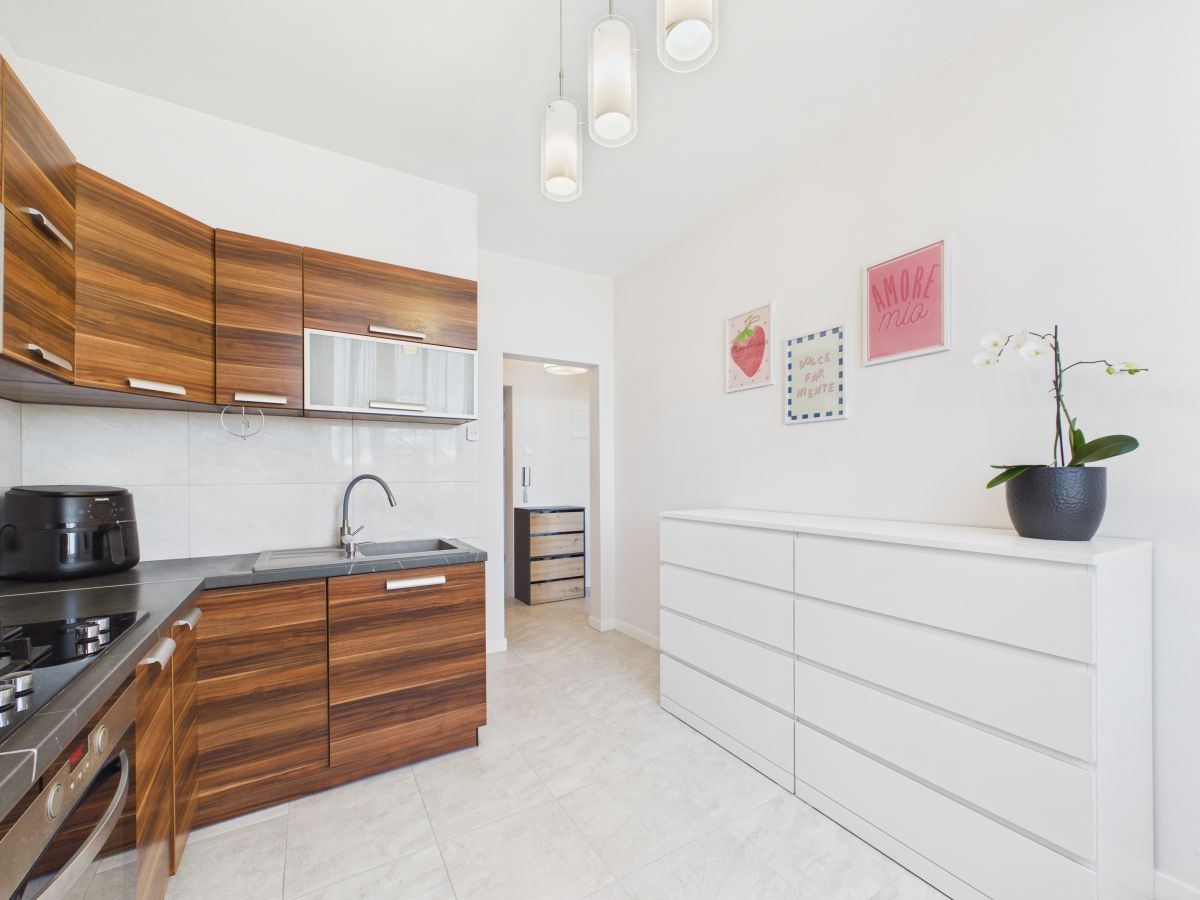 Bright modern kitchen with dark wood cabinets, gray countertop, and a white dresser on the right wall under framed art.