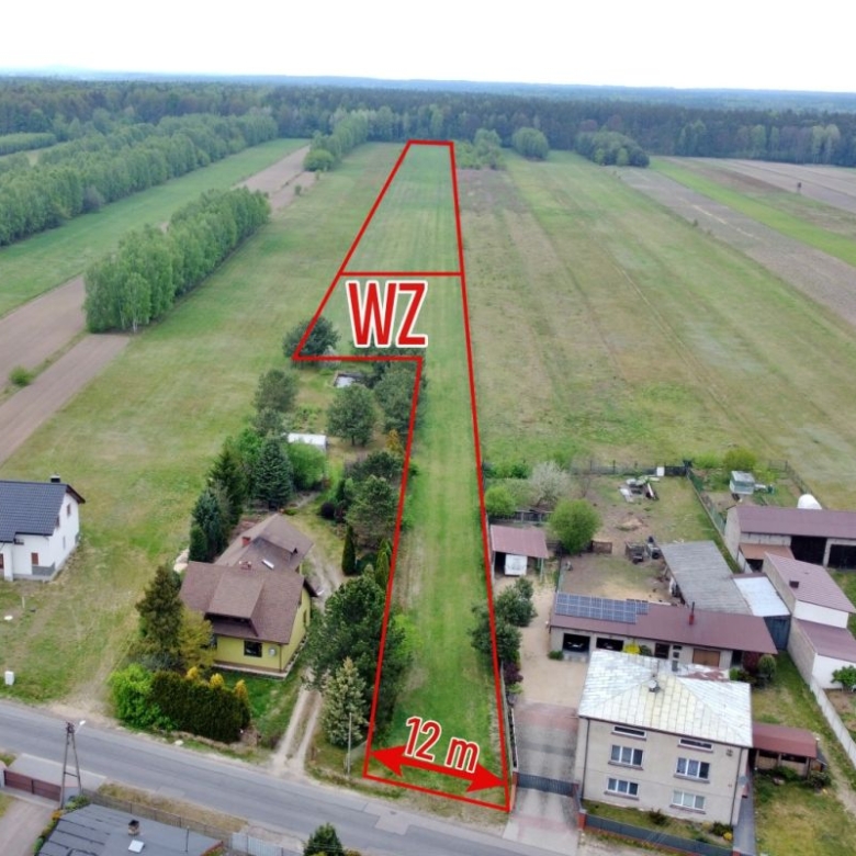 Aerial view of a narrow triangular plot outlined in red along a street, labeled 12 m wide at the road and marked WZ, with nearby houses and fields.