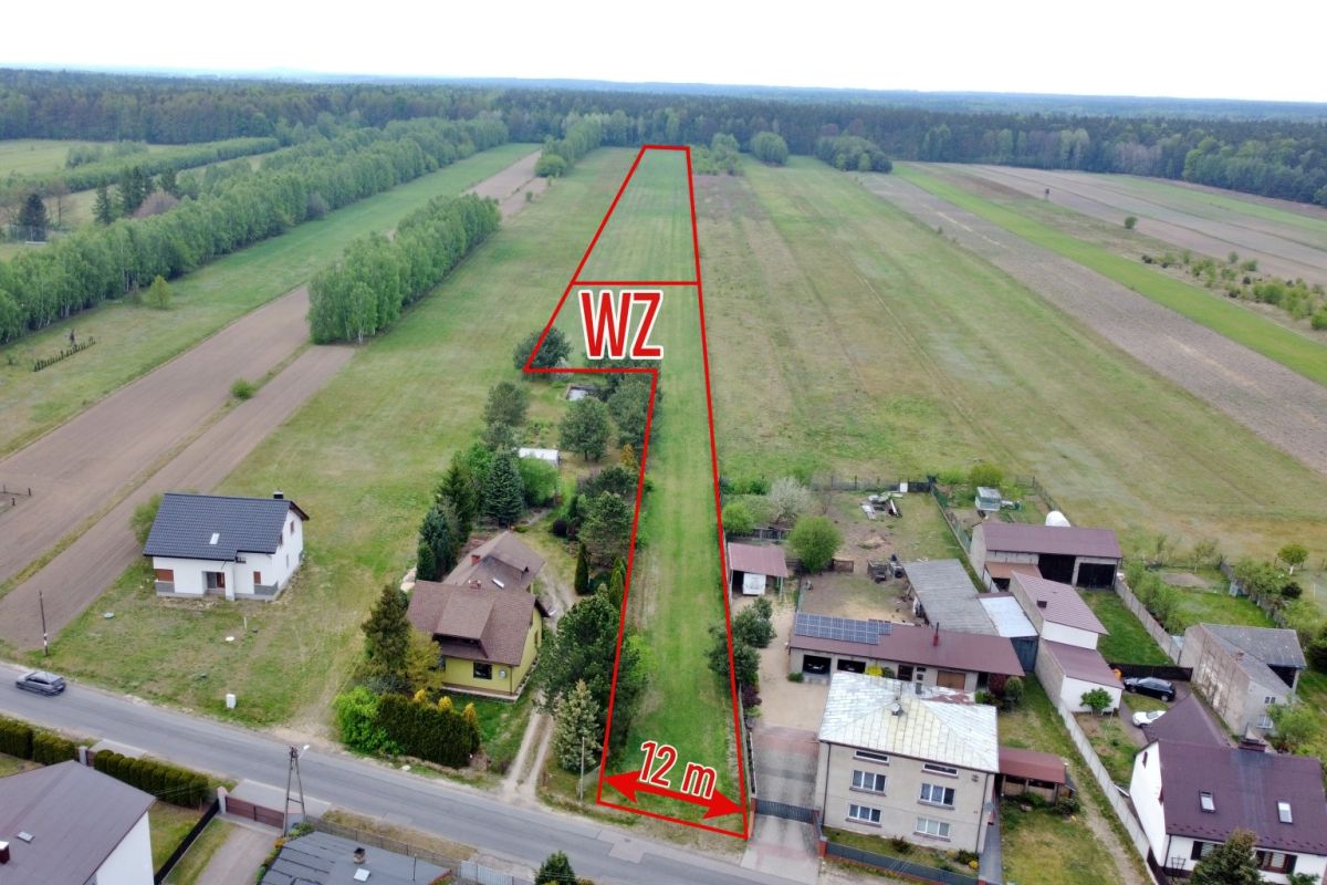 Aerial view of a narrow triangular plot outlined in red along a street, labeled 12 m wide at the road and marked WZ, with nearby houses and fields.