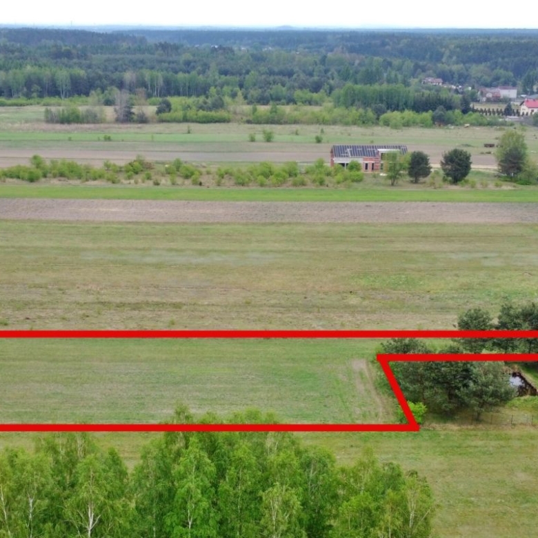 Aerial view showing farmland with a red outline marking a long parcel of land that includes a corner notch near trees.