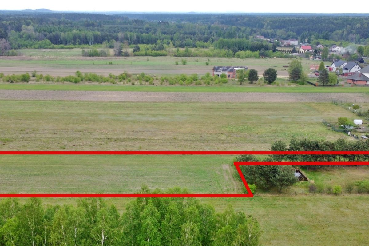 Aerial view showing farmland with a red outline marking a long parcel of land that includes a corner notch near trees.