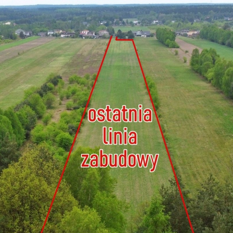Aerial view of a rural field with a red outline marking the last building line and the text 'ostatnia linia zabudowy' across the center.