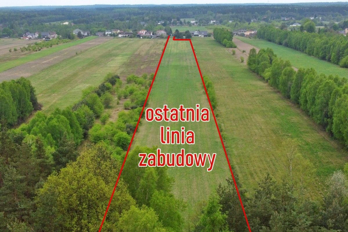 Aerial view of a rural field with a red outline marking the last building line and the text 'ostatnia linia zabudowy' across the center.