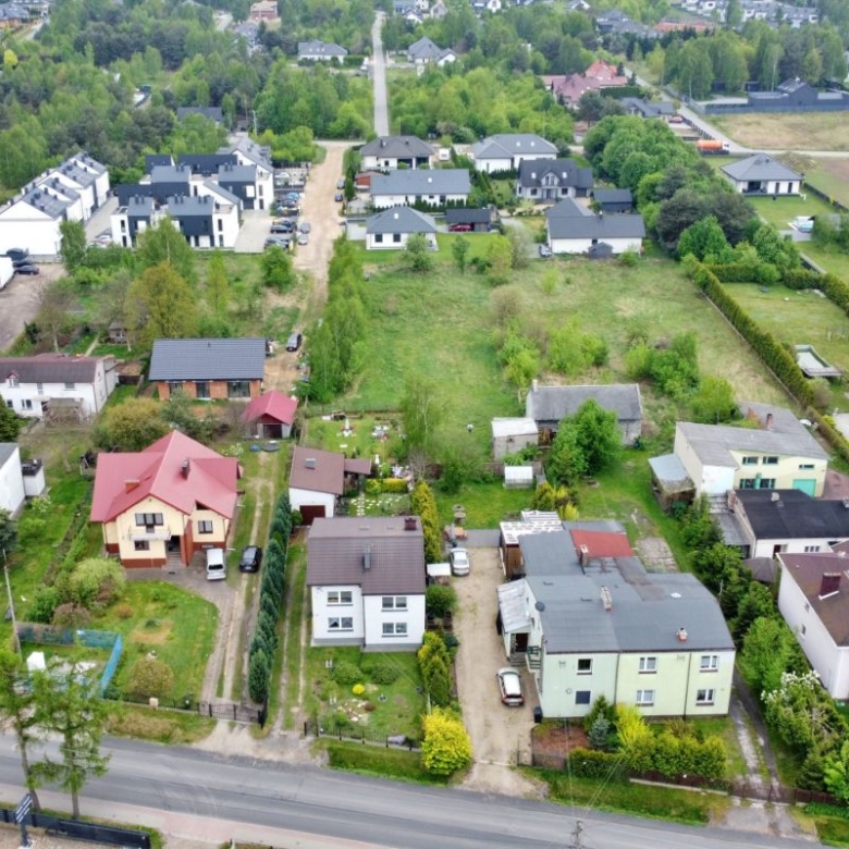 Aerial view of a residential neighborhood with green lawns, trees, and a mix of houses along tree-lined streets.