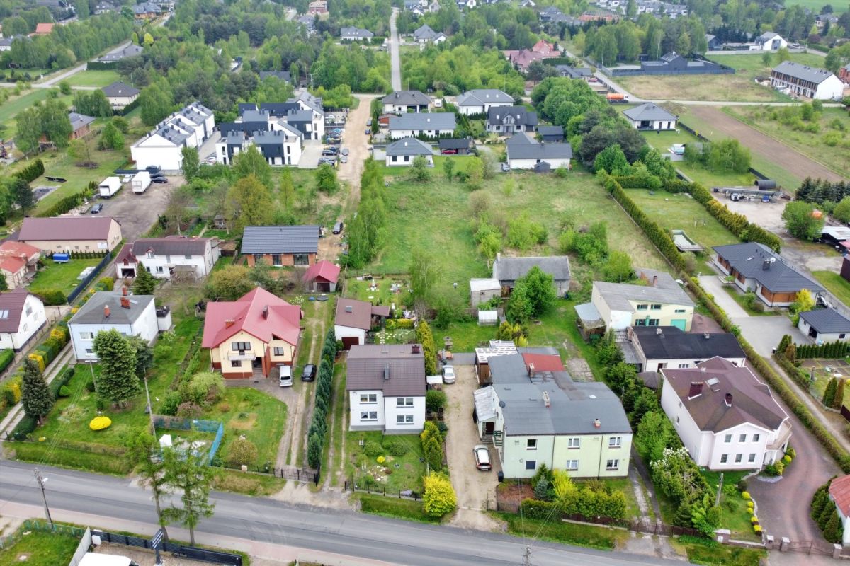 Aerial view of a residential neighborhood with green lawns, trees, and a mix of houses along tree-lined streets.