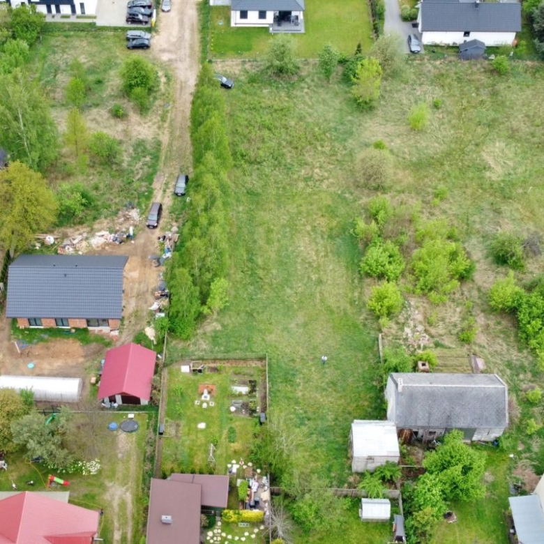 Aerial view of a residential area with a large central grassy lot surrounded by houses and trees .