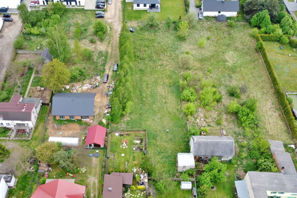Aerial view of a residential area with a large central grassy lot surrounded by houses and trees .