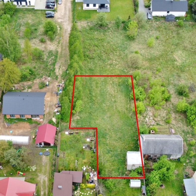 Aerial view of a vacant residential lot outlined in red, bordered by houses and trees in a neighborhood setting.