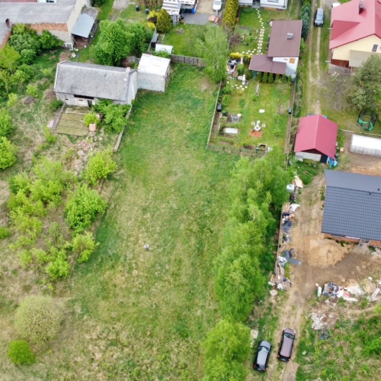 Aerial view of a residential area with green yards and a large central grassy lot surrounded by houses and trees.