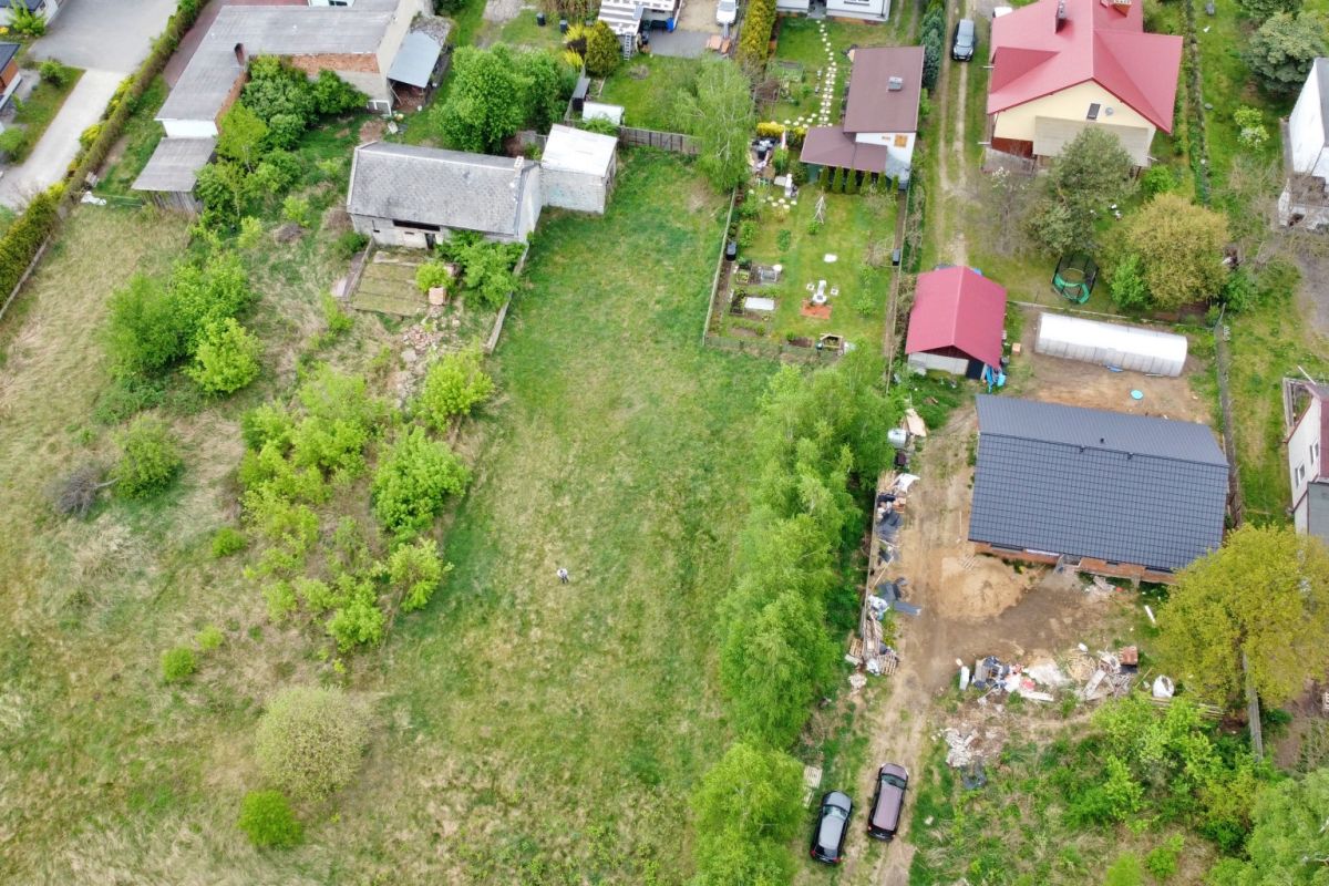 Aerial view of a residential area with green yards and a large central grassy lot surrounded by houses and trees.