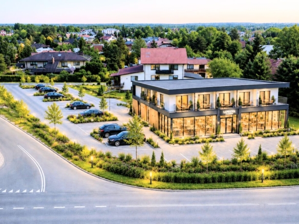 Modern glass-front commercial building labeled Landova, with a parking lot and lush landscaping in a suburban complex.