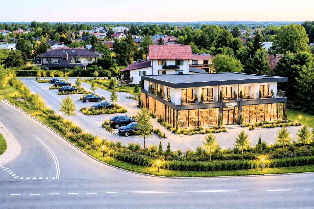 107963768.jpg Modern glass-front commercial building labeled Landova, with a parking lot and lush landscaping in a suburban complex.