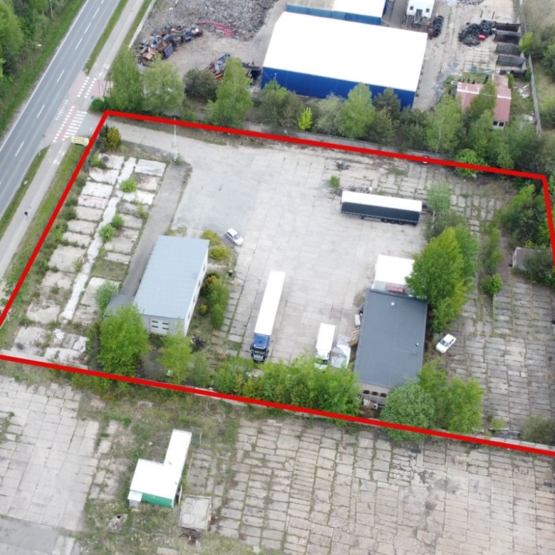 Aerial view of an industrial yard outlined in red, with buildings, trucks, and parked vehicles inside the boundary.