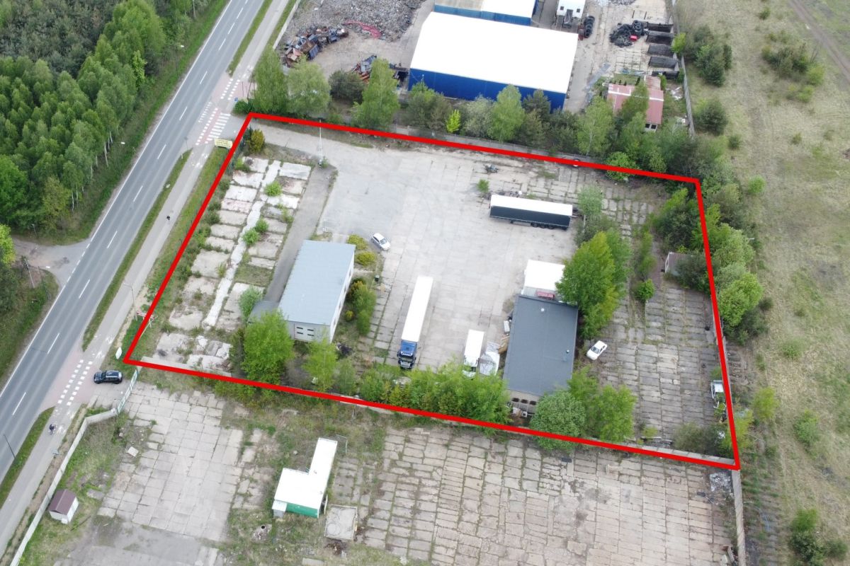 Aerial view of an industrial yard outlined in red, with buildings, trucks, and parked vehicles inside the boundary.