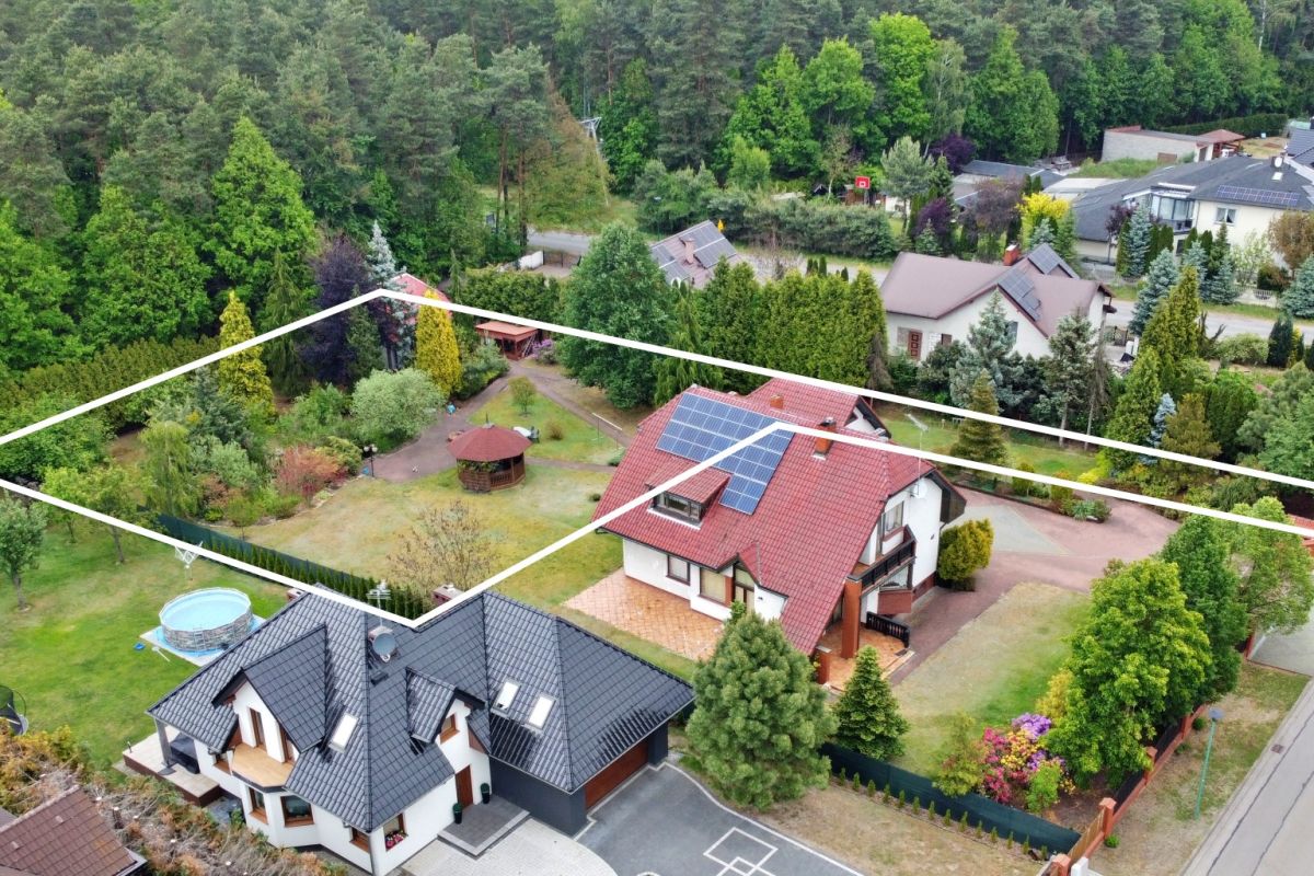 Aerial view of a residential property with white boundary lines marking lot edges; houses, garden, trees, solar panels on the roof, and a circular pool visible in the yard.