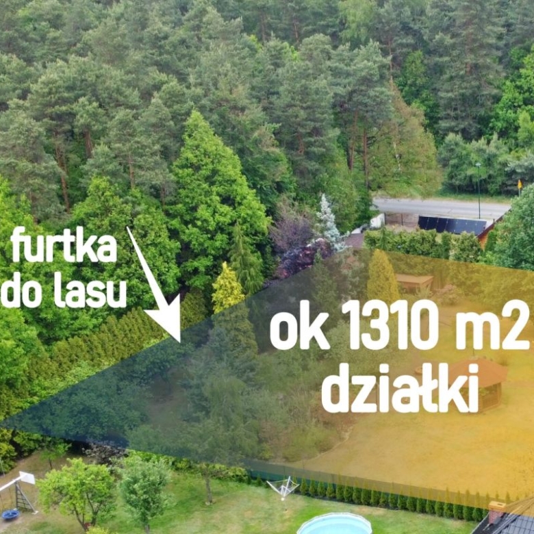 Drone view of a green, tree-filled property with a highlighted plot labeled 'ok 1310 m2 działki' and 'furtka do lasu' indicating forest access (for sale).