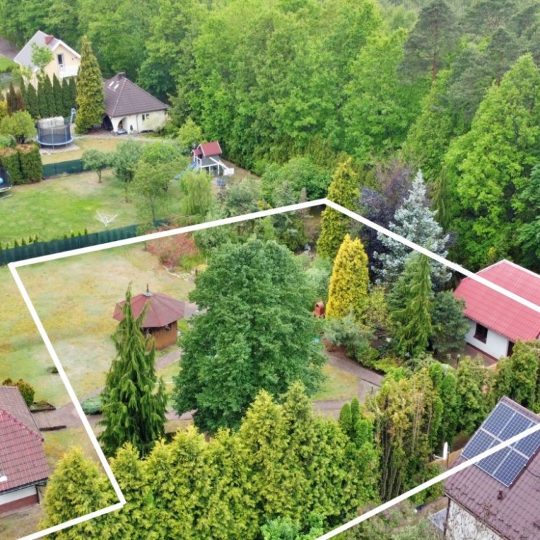 Aerial view of a suburban property with a marked boundary outline showing a central lawn, trees, a gazebo, and surrounding houses.