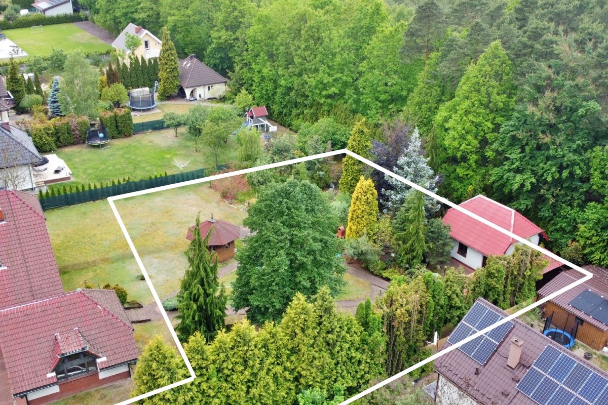 Aerial view of a suburban property with a marked boundary outline showing a central lawn, trees, a gazebo, and surrounding houses.