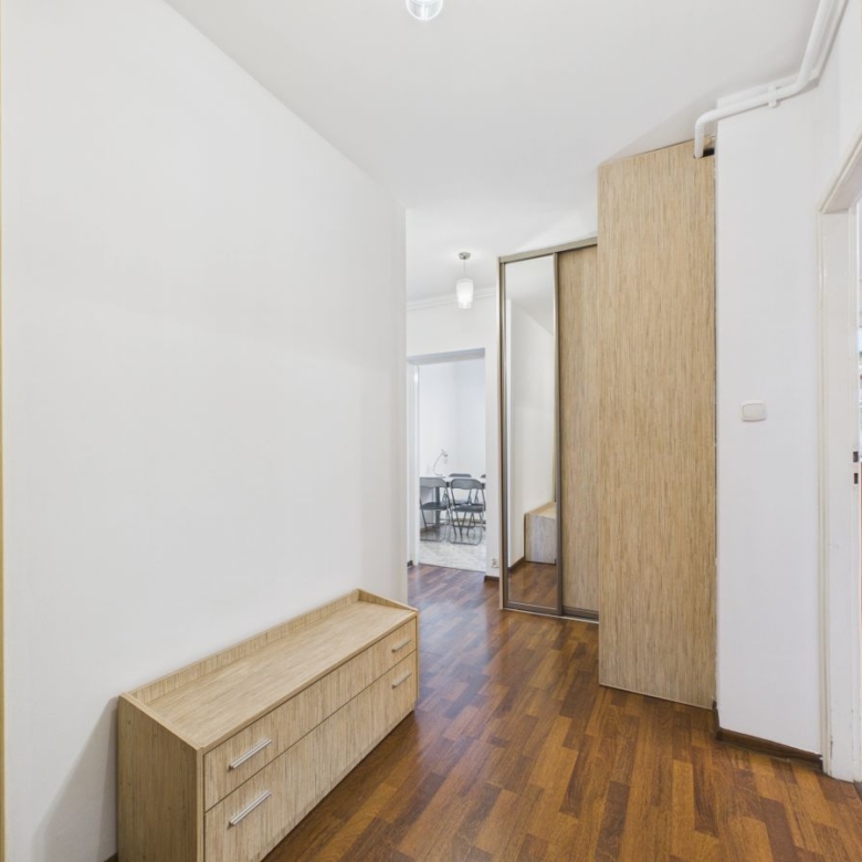 Hallway with white walls, wood floor, and light wood storage units along the left and at the far end.