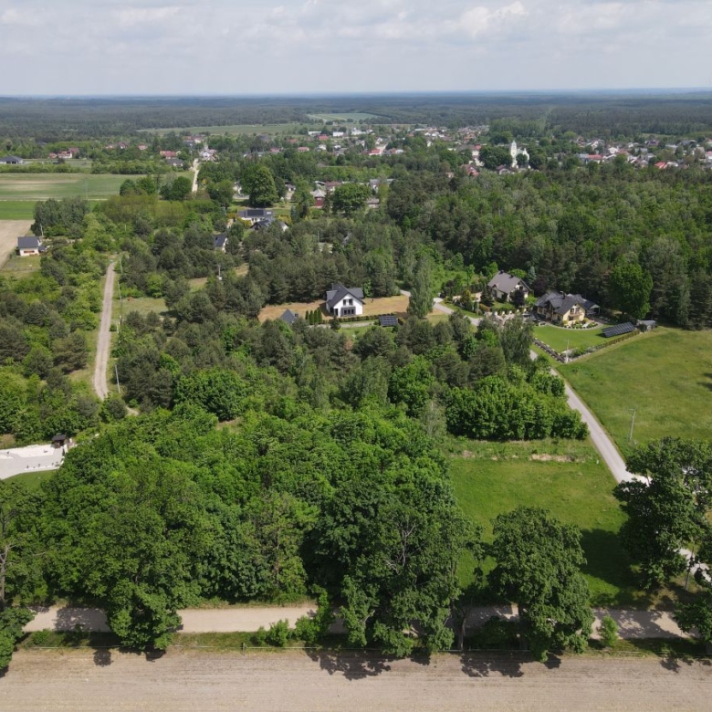 Aerial view of a rural neighborhood with dense trees, winding roads, and scattered houses amid fields and farmland.