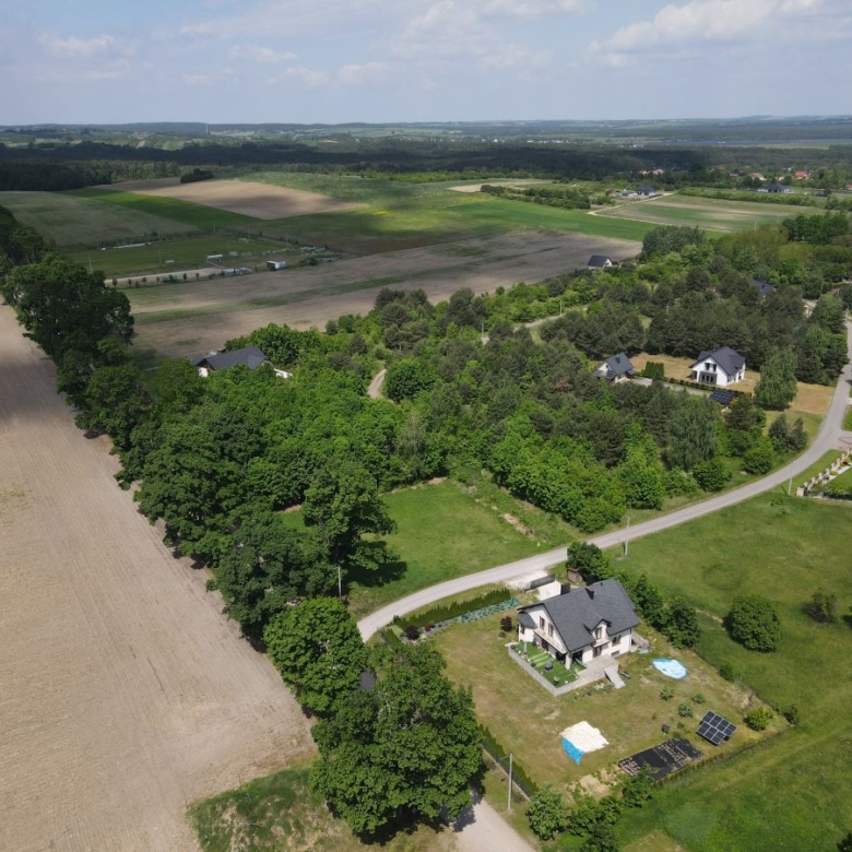 Aerial view of a rural landscape with fields, trees, and scattered houses along a winding road.