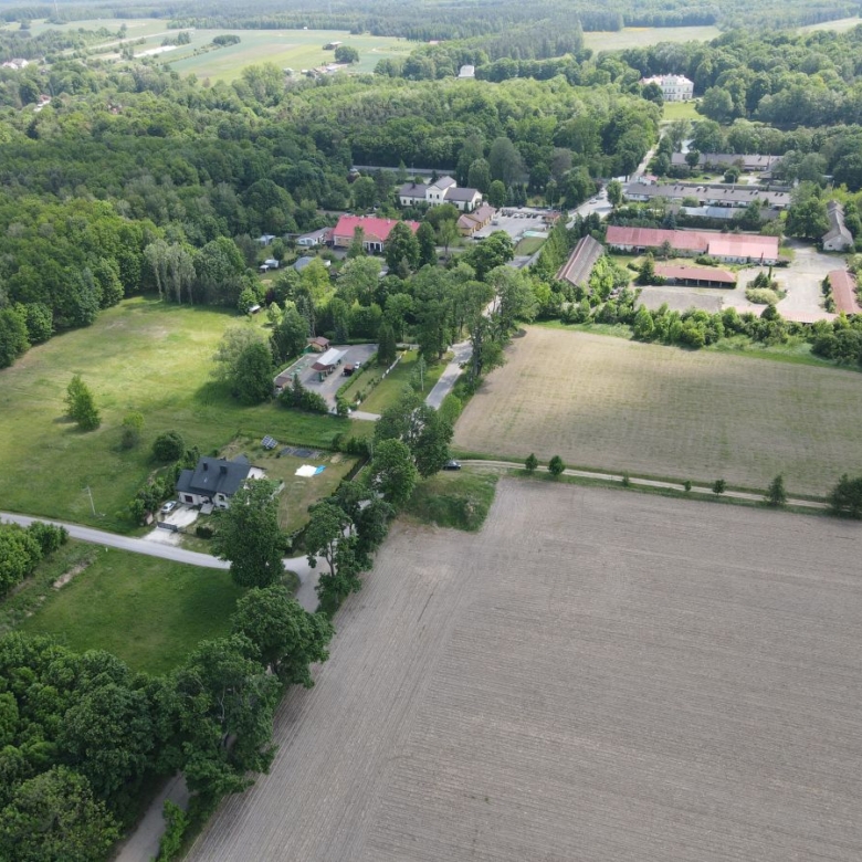 Aerial view of a rural area with farmland, trees, and a cluster of houses along a road.
