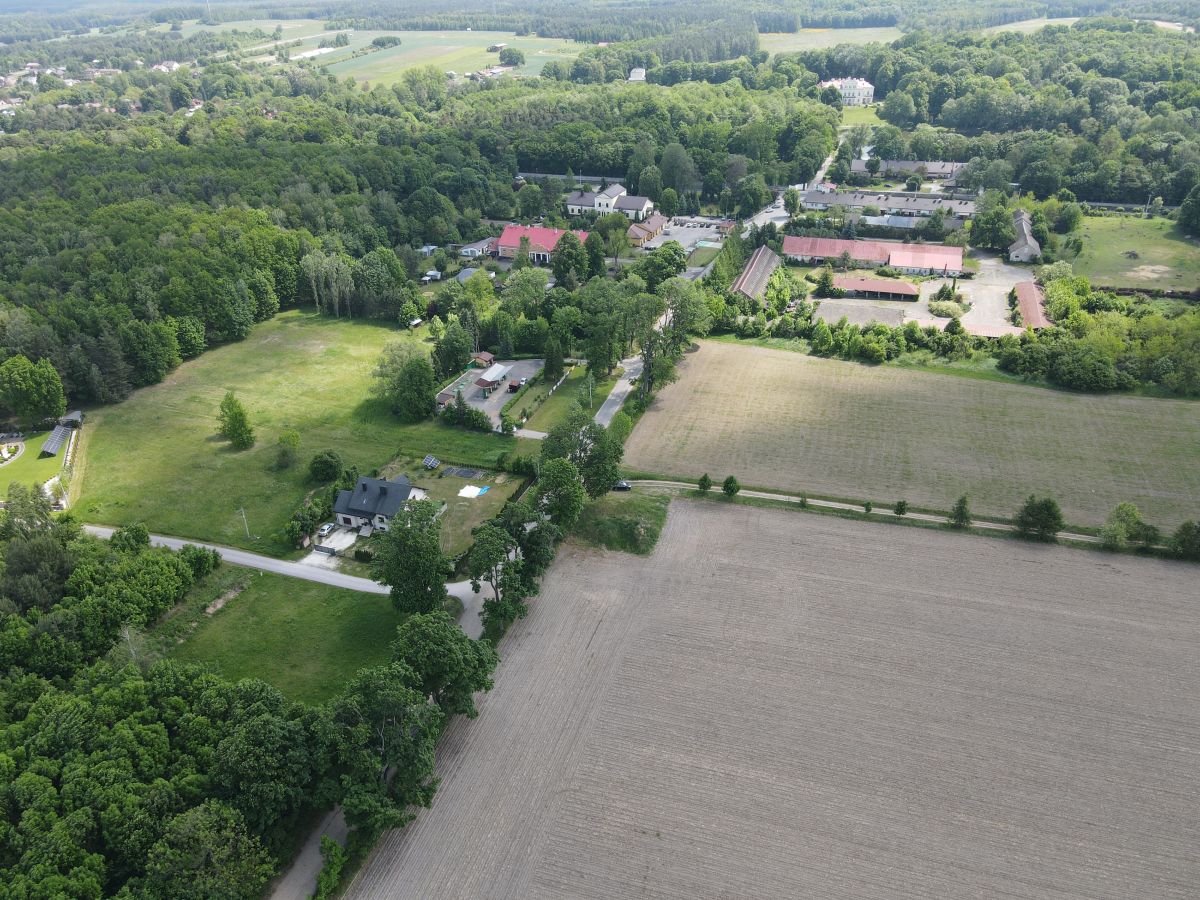 Aerial view of a rural area with farmland, trees, and a cluster of houses along a road.