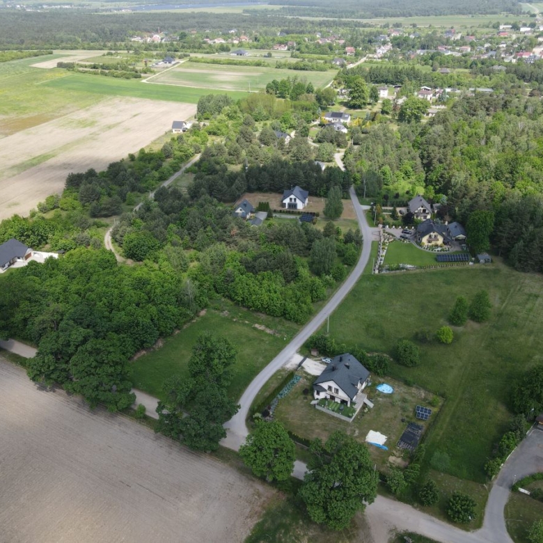 Aerial view of a rural neighborhood with winding road, houses among trees, and surrounding farmland fields.