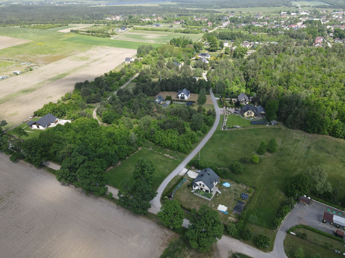 Aerial view of a rural neighborhood with winding road, houses among trees, and surrounding farmland fields.