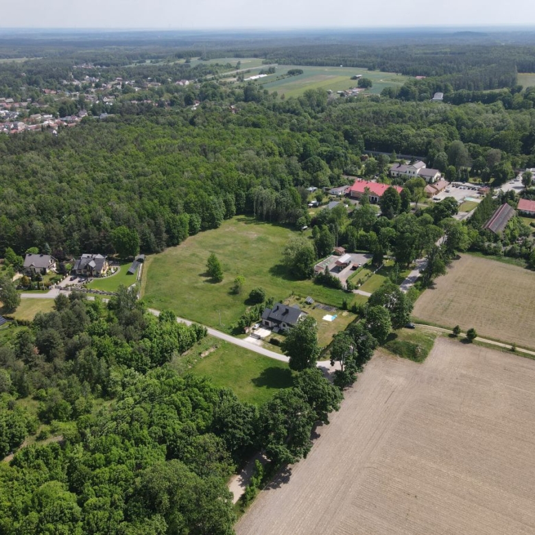 Aerial view of a rural landscape with fields, forests, and a small residential neighborhood