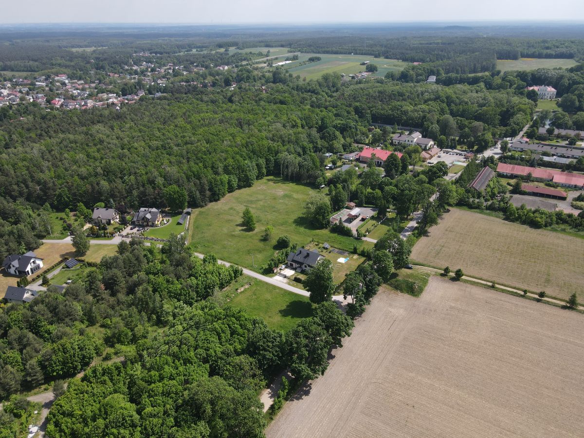 Aerial view of a rural landscape with fields, forests, and a small residential neighborhood