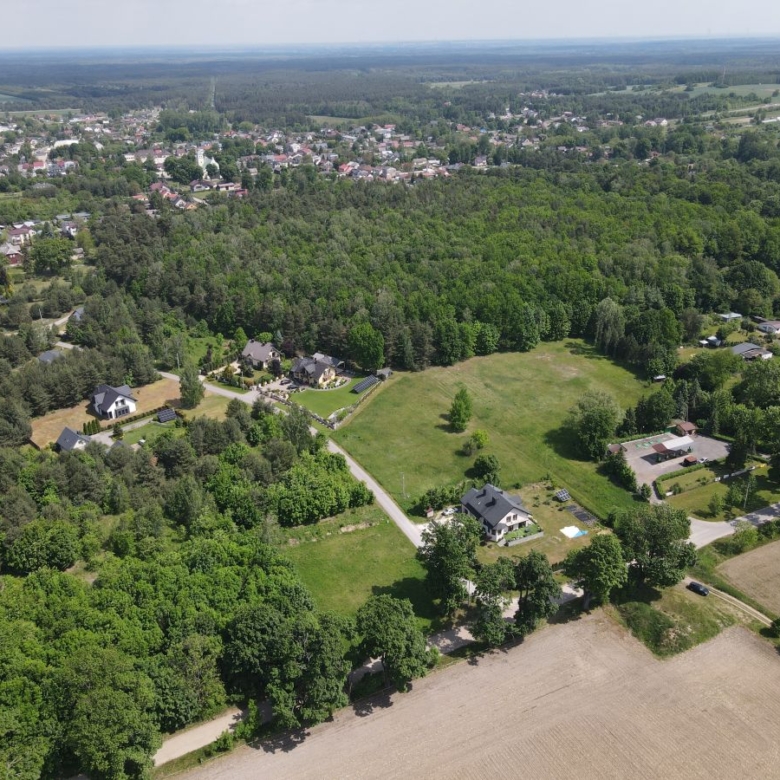 Aerial view of a rural landscape with clusters of houses, roads, fields, and dense tree cover stretching to the horizon.