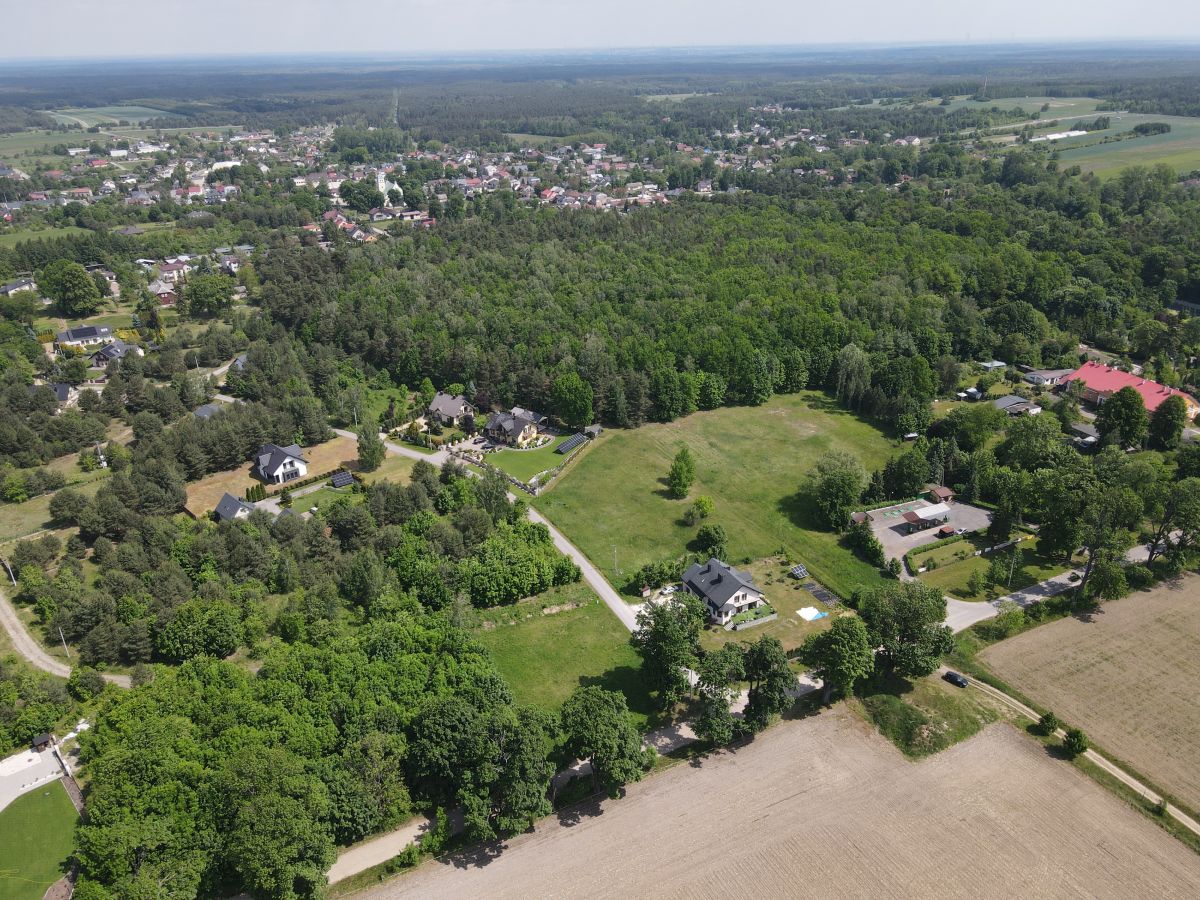 Aerial view of a rural landscape with clusters of houses, roads, fields, and dense tree cover stretching to the horizon.