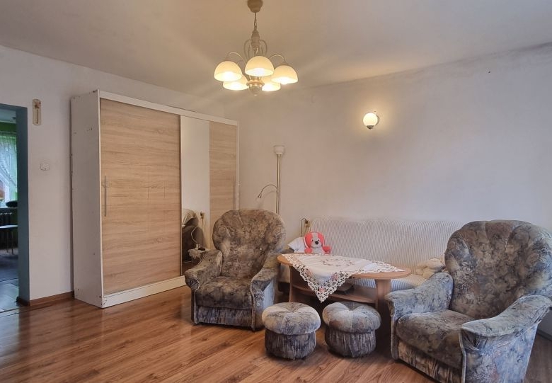 Cozy living room with two floral armchairs, a matching sofa, a lace-covered coffee table, and a wardrobe with mirrored doors.