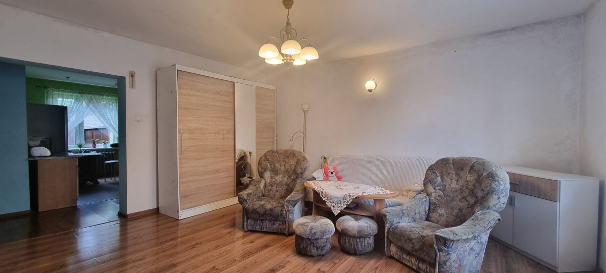 Cozy living room with two floral armchairs, a matching sofa, a lace-covered coffee table, and a wardrobe with mirrored doors.