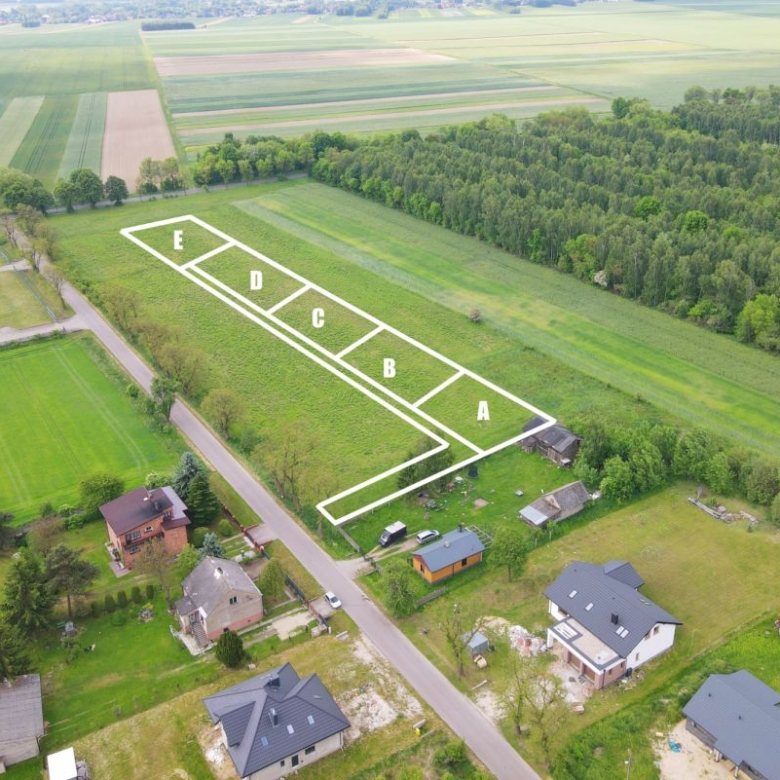 Aerial view of a rural field with five outlined plots labeled A to E in white lines near a small village.