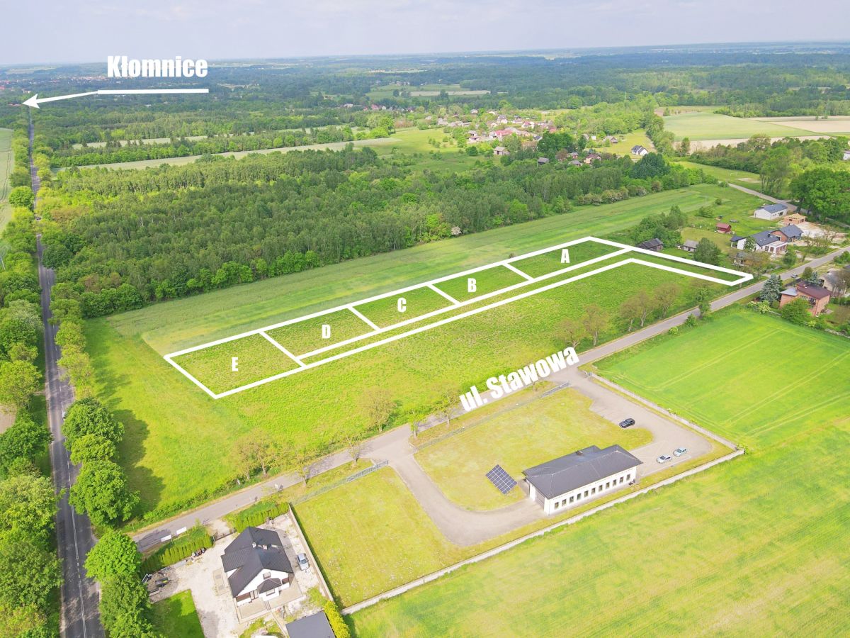 Aerial view of a subdivided plots labeled A–E along ul. Stawowa in a grassy field near a small village marked 'Kłomnice' in the distance.
