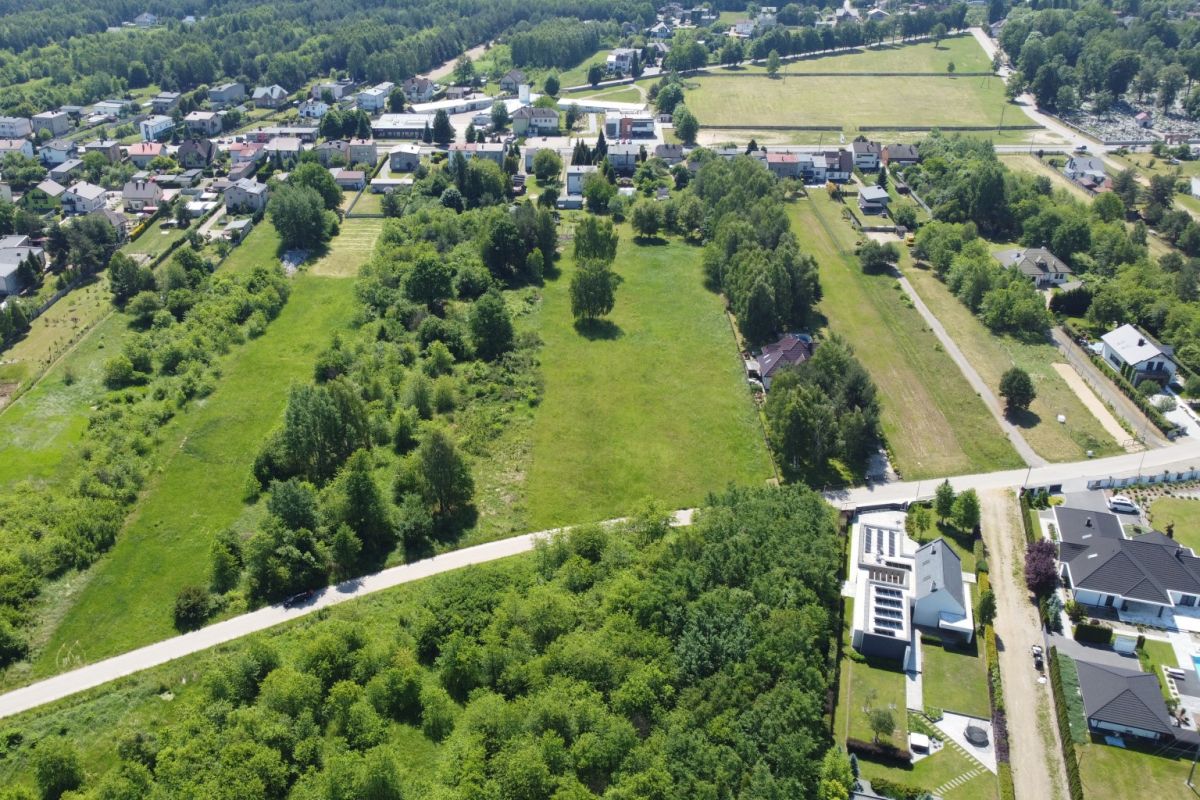 Aerial view of a small town with green fields, trees, and residential streets.