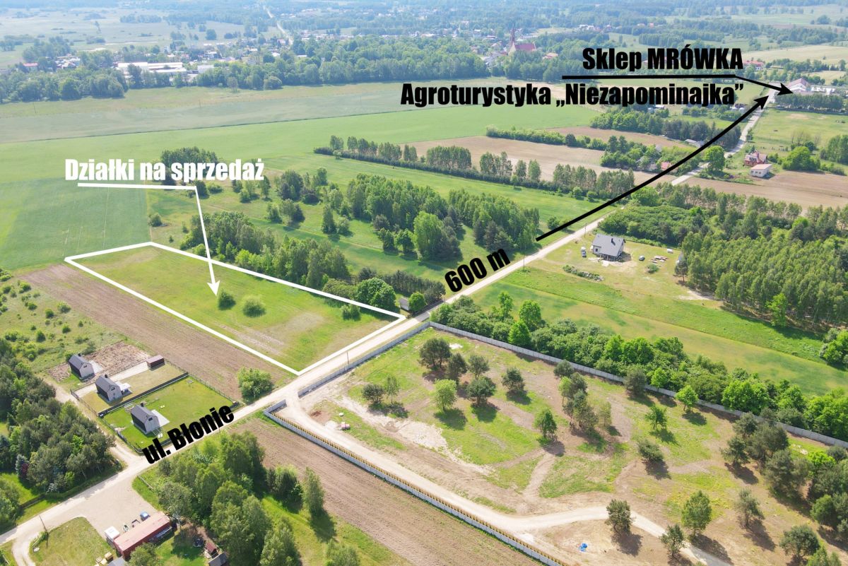 Aerial view of a rural land for sale with outlined plot boundaries and the label 'Działki na sprzedaż' near a road and green fields.