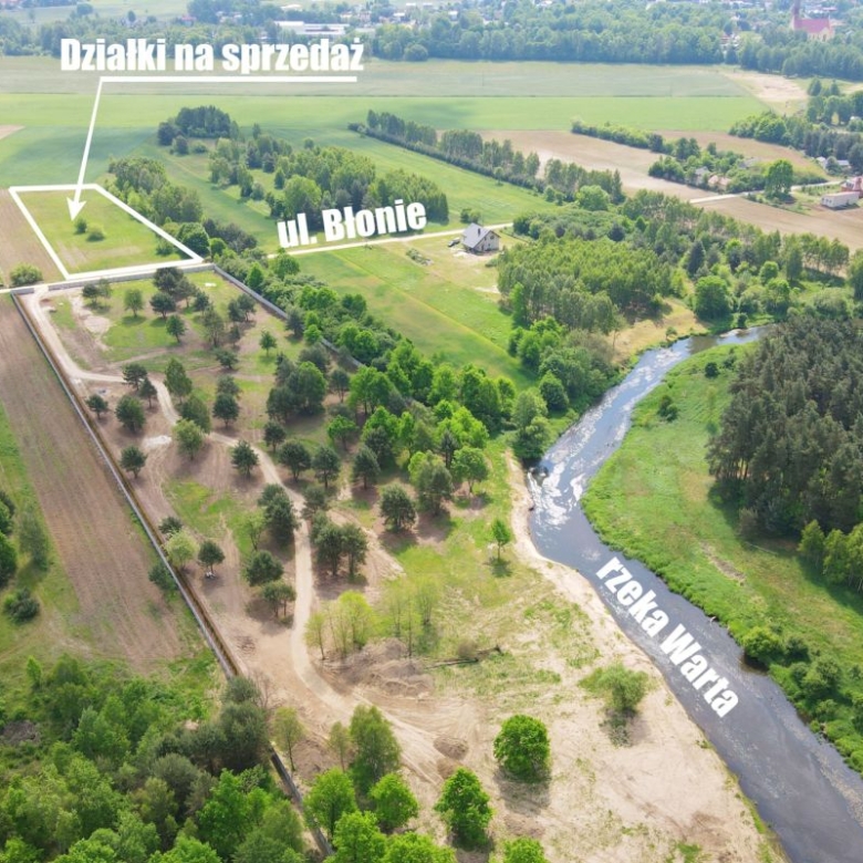 Aerial view of countryside with marked plots for sale labeled 'Działki na sprzedaż', nearby street Ul. Blonie, and the Warta River nearby.